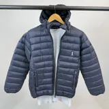 Campera puffer de nylon color azul marino, liviana y con capucha desmontable. Presenta cierre frontal y logo bordado en el pecho.