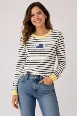 Remera de manga larga a rayas horizontales negras y blancas, con cuello redondo y puños en color celeste. Presenta un bordado central con la bandera de Uruguay y la inscripción 'SOUTH AMERICA' en color azul.