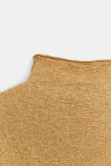 Jersey de punto con textura, color crudo, de cuello subido y manga larga. Presenta un diseño holgado con bajo asimétrico y aberturas laterales.