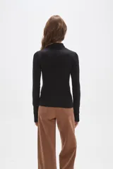 Remera de manga larga color negro, confeccionada en tejido técnico al cuerpo. Presenta cuello tipo polo con cierre frontal parcial y puños con abertura para el pulgar. Incluye un pequeño logo estampado en la manga.