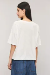 Remera oversize color blanco, confeccionada en jersey Pima flamé de algodón. Cuenta con escote en V, mangas cortas con detalle de bordado en la manga y cintura con elástico que genera un efecto balloon.