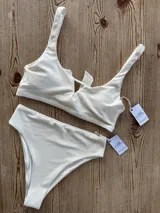 Top de bikini entero color crudo, con textura y abertura triangular en el centro del busto. Se ata en la espalda y tiene copas desmontables.