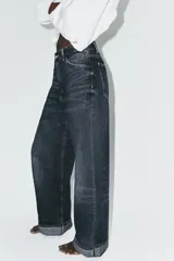 Jeans de tiro medio con corte baggy, cinco bolsillos y bajo con dobladillo. Cierre frontal con cremallera y botón metálico.