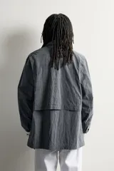 Sobrecamisa relaxed fit de corte amplio, confeccionada en tejido técnico con mezcla de algodón con efecto lavado en color gris oscuro. Cuenta con cuello solapa en pana a tono, cierre frontal con botonadura, manga larga y bolsillos frontales de plastrón con solapa. Pertenece a la colección especial Aaron Levine x Zara.