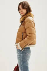 Campera estilo aviador en tonos tostados, con diseño acolchado y paneles de gamuza en la parte superior. Presenta cuello alto con doble hebilla, cierre frontal completo y detalles de corderito sintético en el cuello y el ruedo.