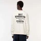 Buzo de felpa color blanco hueso, con cuello redondo y puños y ruedo acanalados. Presenta una pequeña impresión en el pecho con texto que incluye "EAST KENSINGTON PHILADELPHIA".