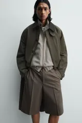 Bermuda de vestir color marrón oscuro, corte relajado y tiro alto, con pliegues frontales y cierre de botón y cremallera.