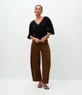 Blusa peplum de viscosa negra con escote en V cruzado, mangas cortas abullonadas con elástico en los puños y cordón ajustable en la cintura.