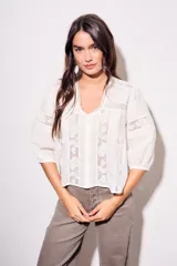 Blusa negra de algodón peinado con calce oversize, escote en V, mangas tres cuartos abullonadas y detalles de encaje y bordados en el frente y mangas.