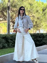 Pantalón ancho color crudo con pespuntes en marrón chocolate, confeccionado en tela con mezcla de jean y lino.