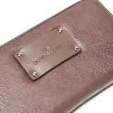 Billetera tipo fichero Extra Large de cuero sintético color marrón con textura granulada y placa metálica frontal con logo grabado.