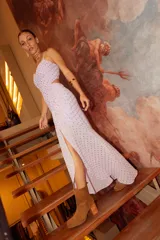 Vestido midi de crepé color fucsia, con escote corazón, tirantes finos cruzados en la espalda y aberturas laterales en la cintura. La falda presenta un diseño con frunces laterales y una abertura frontal que deja ver la pierna.