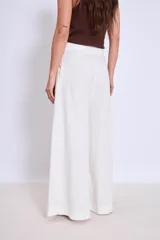 Pantalón palazzo de lino color crudo, con cintura alta y pinzas delanteras.