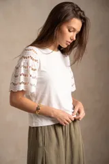 Remera blanca oversize con mangas cortas de encaje perforado con detalles bordados.