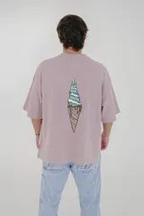 Remera color crema de corte holgado con cuello redondo y mangas cortas. Estampado en el pecho con la inscripción "Pulau Cold Winter" en letras azules y amarillas.