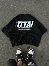 Remera marrón de corte holgado con estampado en la espalda que incluye la palabra "ITTAI" en blanco con líneas rojas y azules, la frase "AN IBIZA PRODUCE" y un texto más pequeño que dice "Ittai Stars Department Gallery - Ibiza Edition. If you're in Ibiza, 112 is not an option.".