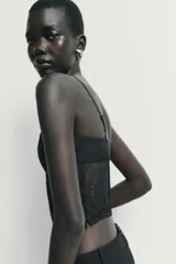 Top estilo corset con copas de tejido satinado y cuerpo de encaje semitransparente con varillas. Presenta tirantes finos ajustables y cierre lateral con cremallera oculta.