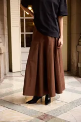 Falda larga de corte acampanado con tablas anchas, confeccionada en algodón color marrón.