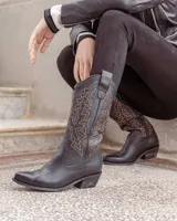 Botas texanas de caña alta confeccionadas en cuero negro, con costuras decorativas en contraste color ocre en la caña y taco cuadrado de madera.