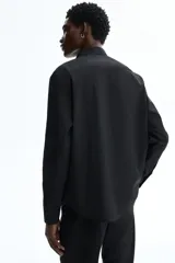 Camisa H&M de manga larga, color negro, con cuello inglés, cierre frontal de botones y corte regular fit.