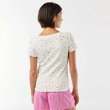 Camiseta de manga corta de punto canalé en color blanco, con estampado de pequeñas flores y terminaciones con volados en cuello, mangas y ruedo.
