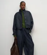 Pantalón de jean estilo aladín con cintura alta y pretina estructurada. Presenta pinzas frontales, volumen en la cadera y piernas con entalle progresivo que finalizan en puños con elástico, logrando un efecto jogger sofisticado.