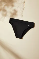 Bombacha tipo bikini de tiro medio, confeccionada en microfibra sin costuras con acabado suave. Presenta un pequeño logo estampado en el lateral y refuerzo interior de algodón.