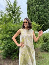 Vestido midi de corte evasé con estampado de hojas en tonos verdes y beige.