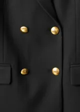 Chaqueta tipo blazer de doble botonadura en color negro, con solapas de muesca, bolsillos frontales con solapa y cierre de botones dorados. Presenta un diseño estructurado con forro interior.