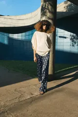 Pantalón de tiro medio con cintura elástica y bolsillos ocultos en costura. Presenta un diseño de corte recto con dobladillo ancho en el bajo y un estampado geométrico sobre fondo oscuro.