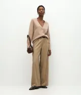 Cardigan de punto color beige con escote en V, cierre frontal con botones grandes y mangas largas con puños acanalados. Presenta un corte recto y estructurado.