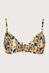Top de bikini tipo triángulo con estampado de hojas en tonos mostaza, negro y blanco. Presenta tirantes delgados ajustables y un accesorio metálico dorado con forma de hoja en el centro del busto.
