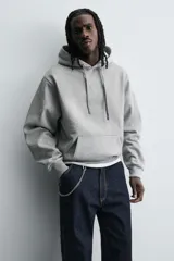 Sudadera tipo hoodie de corte relajado, confeccionada en tejido de algodón con interior cepillado. Presenta capucha con cordones ajustables, bolsillo frontal tipo canguro y terminaciones en rib en puños y ruedo.