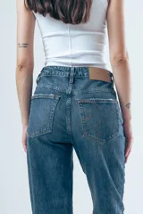 Jean de tiro alto con corte de pierna recta y diseño clásico de cinco bolsillos. Confeccionado en denim de tono azul medio con costuras en contraste.