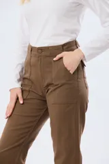 Pantalón de gabardina marrón, de corte recto con pinza en el bajo y detalles de botones en los tobillos.