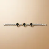 Pulsera de diseño articulado en plata y oro, con eslabones de malla metálica y dijes circulares con piedra ónix negra en el centro.