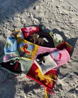 Sweater de lana tejido y bordado a mano con diseño patchwork de animales y motivos geométricos en tonos rojo, verde, marrón, beige y negro.