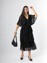 Vestido midi de seda italiana color marrón, con escote en V, mangas murciélago holgadas y falda en capas con volados. Cuenta con cintura elastizada y lazo ajustable al tono.