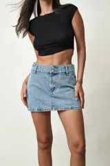 Short pollera de jean de tiro medio, color azul claro, con doble botón en la cintura y diseño de falda corta al frente con pantalón corto interno.