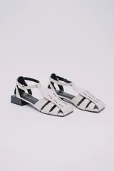 Sandalias de cuero estilo jaula con punta cuadrada y taco bloque bajo de color negro. Presentan un diseño de tiras entrelazadas en la capellada y cierre con hebilla ajustable en el tobillo.