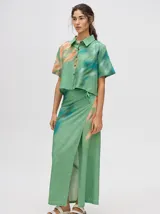 Falda midi tipo pareo color verde con estampado estilo tie-dye en tonos azul, naranja y blanco, con tiras ajustables en la cintura.