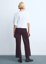 Jeans color bordó, de corte wide leg y tiro medio, con bolsillos laterales y traseros, y terminación sin dobladillo en los tobillos.