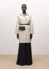 Chaqueta larga de algodón color beige, de diseño recto, manga larga, cuello camisero y cierre delantero con botones ocultos. Cuenta con dos bolsillos laterales con solapa.