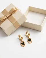 Caravanas tipo argolla con dije colgante en forma de mano de Fátima con un corazón negro en el centro, confeccionadas en acero dorado.