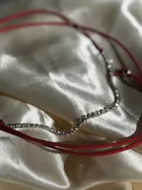 Gargantilla de strass plateado con tiento rojo.