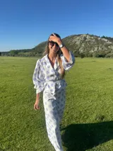 Camisa blanca con lunares celestes, de corte clásico, con cuello camisero y mangas largas abullonadas.