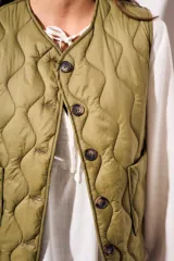 Chaleco verde militar con diseño acolchado y cierre frontal con botones.