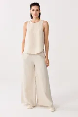 Pantalón de lino color beige, de cintura alta con elástico, bolsillos laterales y corte palazzo.