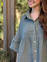 Vestido camisero blanco de lino italiano, con cuello camisero, cierre frontal con botones, mangas cortas con doble volado y bolsillos laterales.