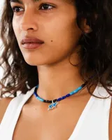 Collar de cuentas cilíndricas en tonos azules y negros, con un dije central de dos estrellas esmaltadas en azul con borde plateado.